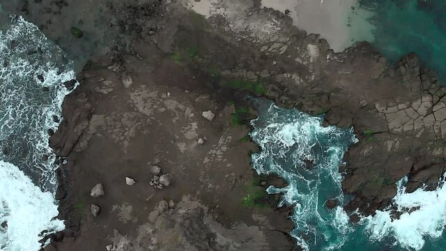 Turbulent sea wave aerial top down view from drone flying above rock beach