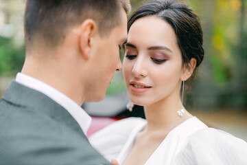Amazing smiling wedding couple. Pretty bride in fashion white wedding dress and stylish groom in gray tuxedo