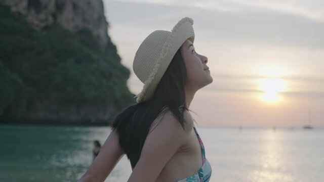 A beautiful black hair woman enjoying a natural seascape in evening vibe before leaving, after sun bathing activity, summer travelling trip, going to sea on weekend, wearing a cute bikini on beach