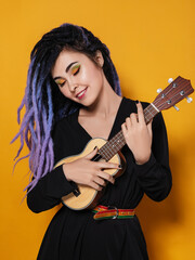 beautiful young woman with lilac dreadlocks and multi-colored makeup stands on a yellow studio...