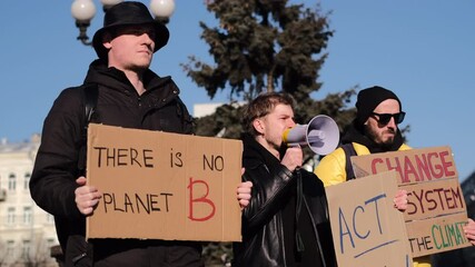 A group of people with banners and a megaphone in hand are protesting in the city square for svae planet clean world act now    
