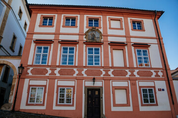 Fototapeta premium Red Baroque Canonical house or Kanovnicky dum at Hradcany Square nearby Prague Castle, sunny winter day, Prague, Czech Republic