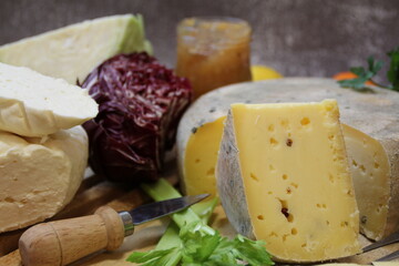 cheese boards, vegetables and quince mustard, white fresh cheese and yellow long-ripening cheese, cheese with pepper, table set with cheese