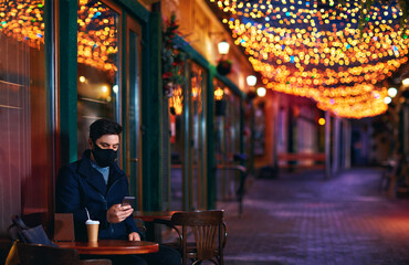 young adult man sitting alone in street cafe on lonely cozy narrow street