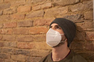 Man wearing FFP2 mask, brick wall, urban