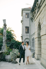 stylish wedding couple strolls against a backdrop of magnificent garden views. A young and stylish bride in a trendy wedding dress and a handsome groom at a wedding for two.