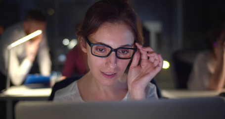 Businesswoman working with colleagues in dark office.