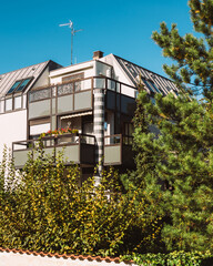 Modern apartment building on a warm summer day with clear blue sky and green bushes and pine tree in the garden