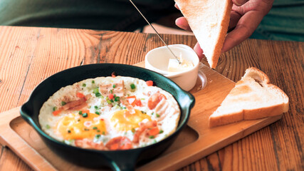 Man spreading butter on the bread with Pan Fried Egg with Toppings 