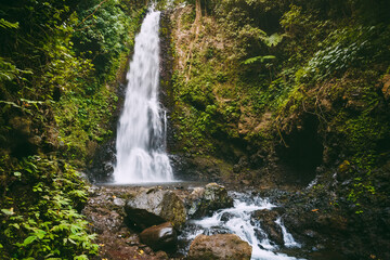 Fototapeta na wymiar Powerful waterfall and rock with stones. Waterfall in Bali