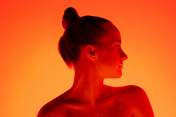 Fire. Handsome woman's portrait isolated on orange studio background in neon light, monochrome. Beautiful female model. Concept of human emotions, facial expression, sales, ad, fashion and beauty.