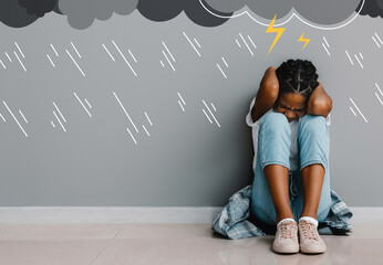 Stressed African-American girl sitting near grey wall