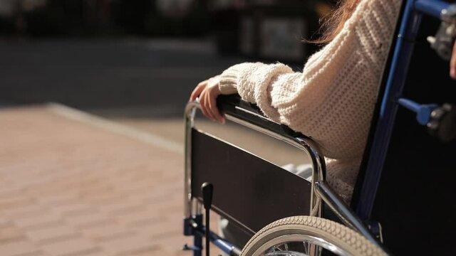 Help and support for disabled invalid people. Man put his hand on hand of disabled woman on wheelchair, close up faceless shot