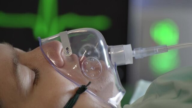 Young woman is breathing with oxygen mask on face in hospital during covid-19 pandemic.