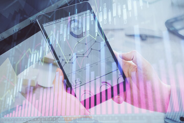 Double exposure of man's hands holding and using a phone and financial graph drawing. Analysis concept.