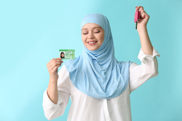 Happy Muslim woman with driving license and car key on color background