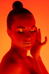 Party. Handsome woman's portrait isolated on orange studio background in neon light, monochrome. Beautiful female model. Concept of human emotions, facial expression, sales, ad, fashion and beauty.