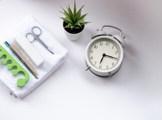 a white alarm clock and a green potted plant on a light background. White, terry towel with buff,...
