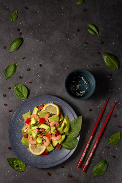 Japanese avocado salad with shrimp and herbs on a gray background. Image with space for text and top view