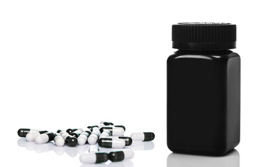 Black plastic jar and capsules on white background