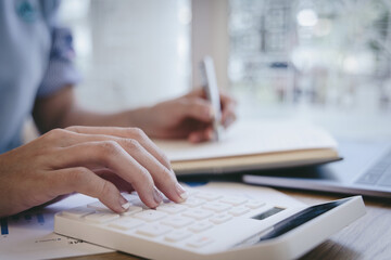 Financial or accounting professionals use a laptop to analyze the company's revenue-expenses graph to prepare for presentation to the chief executive and partner, businesswomen working in the room.