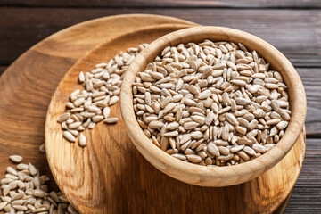 Bowl with sunflower seeds on wooden background