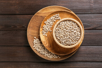 Bowl with sunflower seeds on wooden background