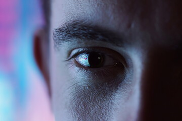 Closeup of an eye with blurred blue and pink neon light background and high contrast. Nightlife - Man in the disco staring at you - obrazy, fototapety, plakaty