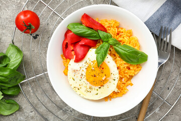 Plate with tasty egg, pepper and rice on gray background