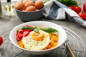 Plate with tasty egg, pepper and rice on gray background