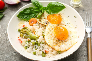 Plate tasty eggs, vegetables and rice on gray background