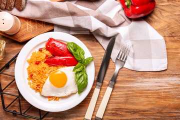Plate with tasty egg, pepper and rice on wooden background