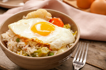 Bowl with tasty egg, vegetables and rice on wooden background