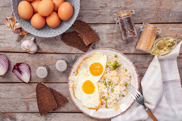 Plate with tasty eggs, vegetables and rice on wooden background