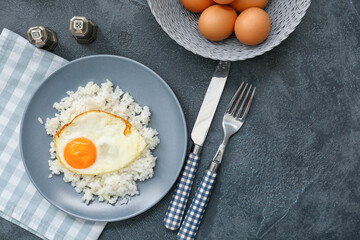 Plate with tasty egg and rice on dark background