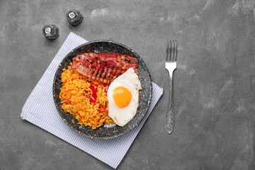 Plate with tasty egg, bacon and rice on dark background