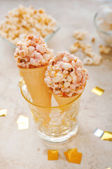 Waffle cones with popcorn balls in glass on light background