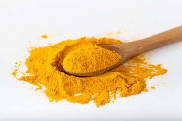 Turmeric or curcuma powder. Turmeric powder in a wooden spoon lay flat isolated over white...