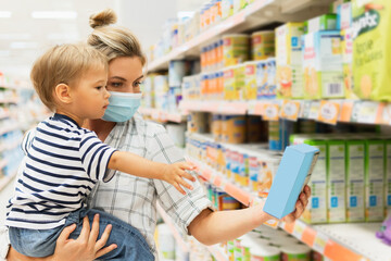 Mother and her little son in a supermarket during virus pandemic