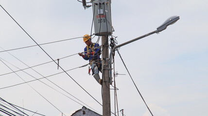 Electrician lineman repairman worker at climbing work on electric post power pole