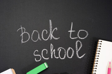 lettering back to school in white chalk on a black school board