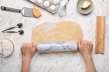 Woman making dough on light background