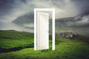 open white door in a natural landscape with sea and land.