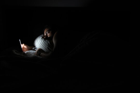 Young man looking at phone in bed