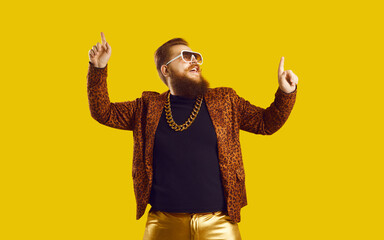 Funny cheerful red haired bearded overweight man hipster in leopard jacket, golden trousers, chain...
