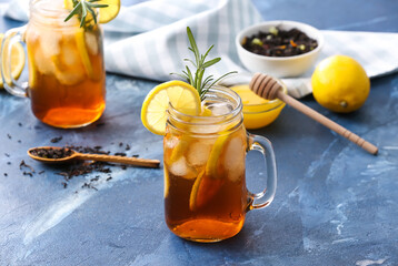Mason jars of cold black tea with lemon on color background