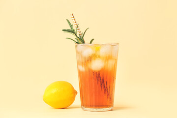 Glass of cold black tea with lemon on color background
