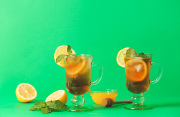 Cups of cold black tea with lemon on color background