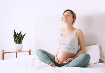 Pregnant woman in lotus pose doing meditation or breathing exercises for healthy pregnancy and...