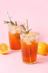 Glasses of cold black tea with lemon on color background
